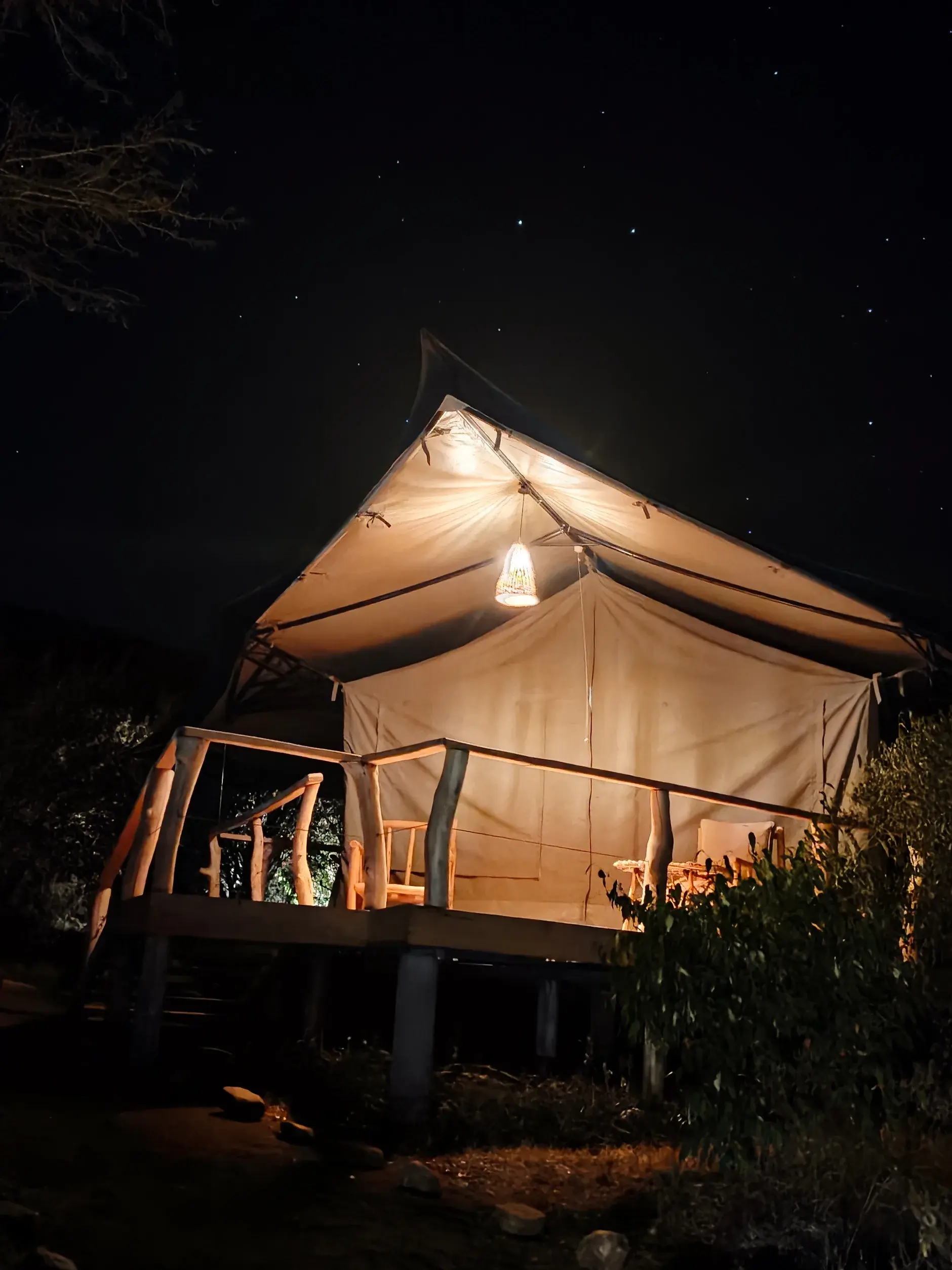 A luxury tent lit up under a starry night sky