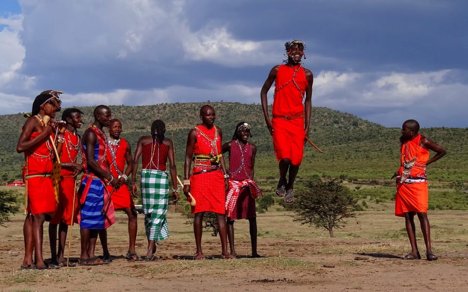 A group of young Maasai men in red shukas doing the adumu jumping dance in the Maasai Mara